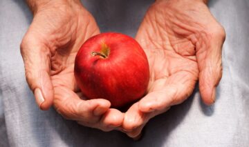 O femeie în vârstă care ține un măr în palme