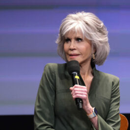 Jane Fonda, într-un sacou verde, în timp ce vorbește la microfon