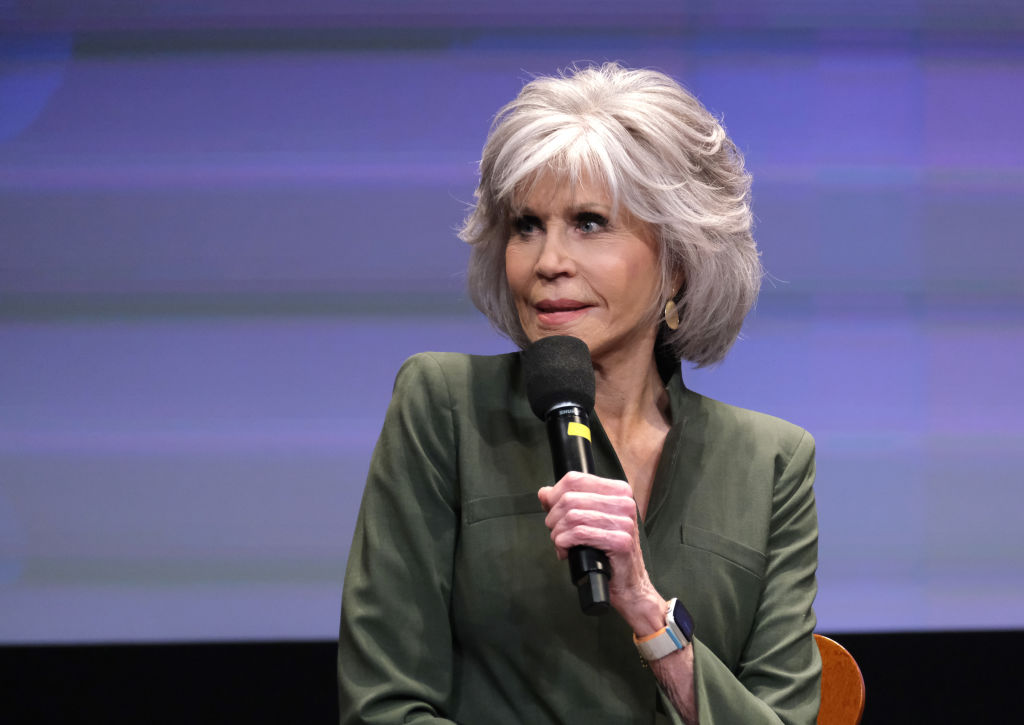 Jane Fonda, într-un sacou verde, în timp ce vorbește la microfon
