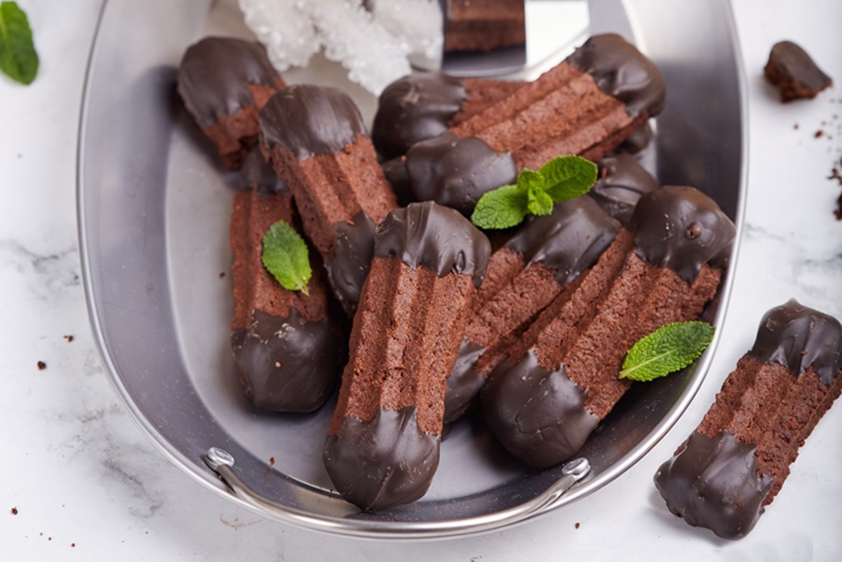 Biscuiți șprițați cu ciocolată pe un platou, decorați cu frunze de mentă