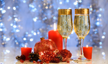 Rodie pe o masă de Anul Nou cu două pahare de șampanie
