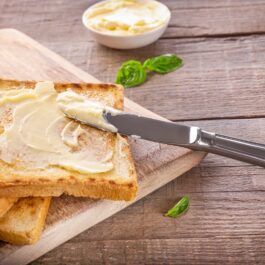Două felii de pâine prăjită pe care se află unt pentru a ilustra ce se întâmplă în corpul tău dacă mănânci zilnic unt