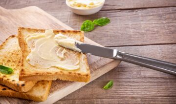 Două felii de pâine prăjită pe care se află unt pentru a ilustra ce se întâmplă în corpul tău dacă mănânci zilnic unt