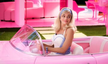 Margot Robbie în timp ce conduce o mașină roz într-o scenă din filmul Barbie
