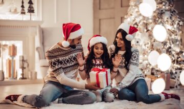 O familie formată dintr-o mamă, un tată și o fetiță în timp ce își oferă cadourile în dimineața de Crăciun ca parte a unei tradiții