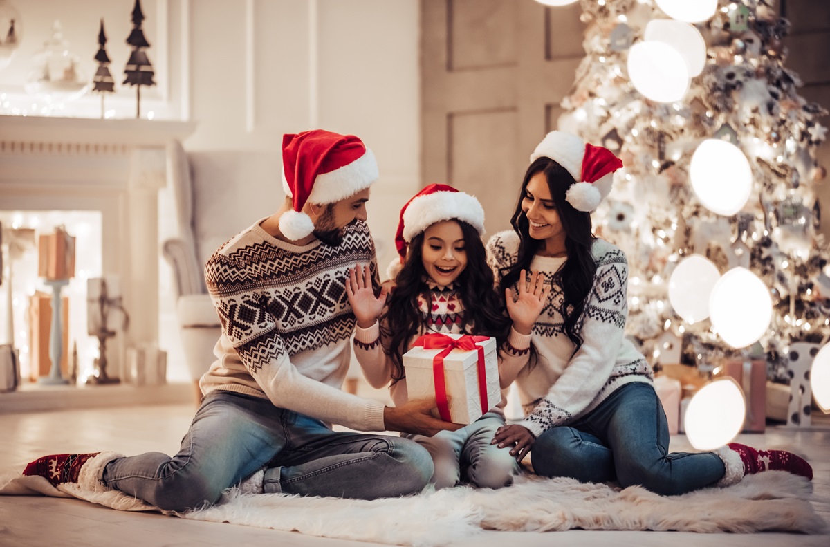 O familie formată dintr-o mamă, un tată și o fetiță în timp ce își oferă cadourile în dimineața de Crăciun ca parte a unei tradiții