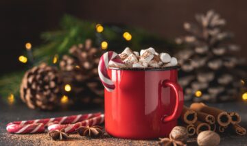 Ciocolată caldă pentru dimineața de Crăciun decorată cu bezele și pusă într-o ceșacă roșie