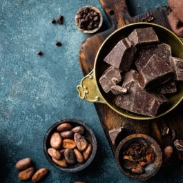 Un bol în care se află mai multe cuburi de ciocolată neagră, o comoară pentru sănătatea organismului