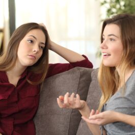 Două femei care stau de vorbă una cu cealaltă în timp ce una dintre ele este mințită