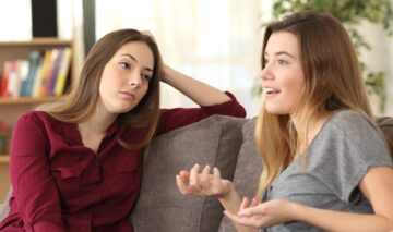 Două femei care stau de vorbă una cu cealaltă în timp ce una dintre ele este mințită