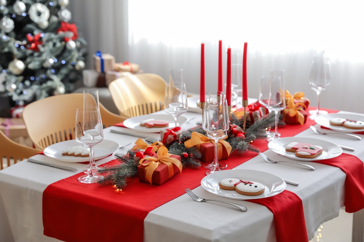 O masă cu decoruri de Crăciun pe care se află lumânări, farfurii și pahare speciale