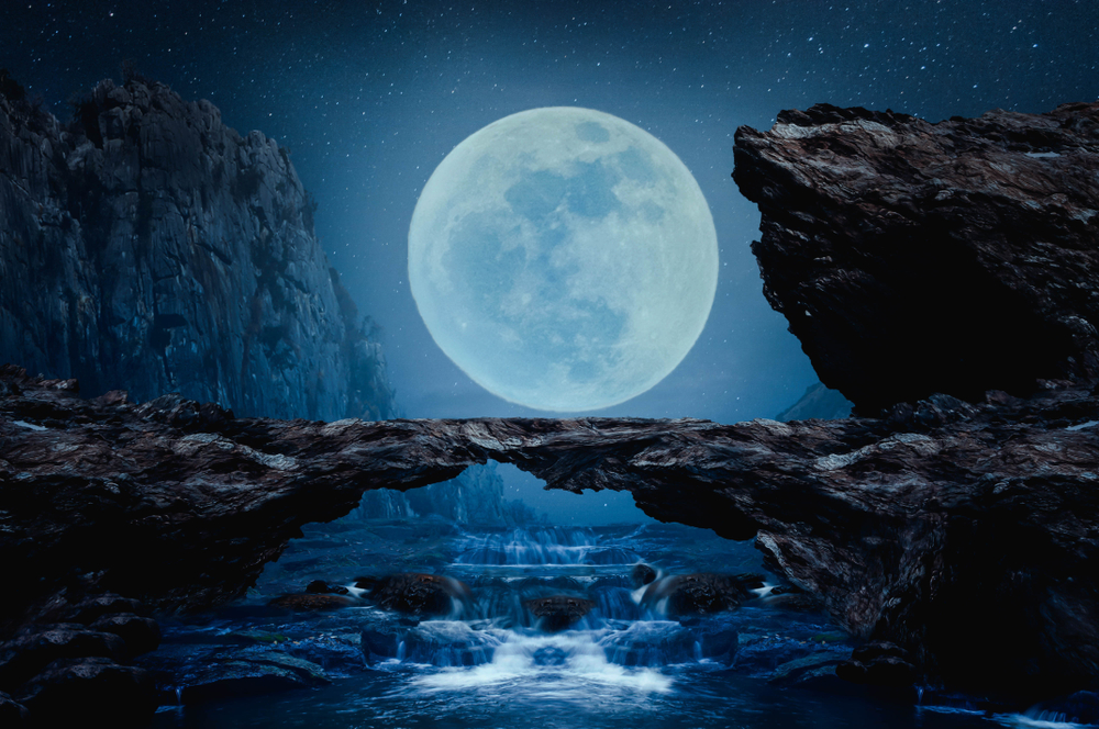 Lună plină pe un cer întunecat lângă un pod de piatră
