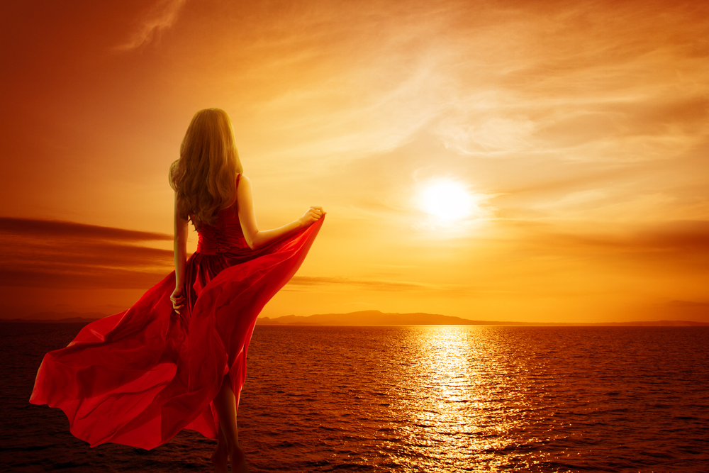 fată frumoasă îmbrăcată într-o rochie lungă privește spre soare