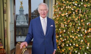 Regele Charles în timp ce pozează în fața bradului de Crăciun