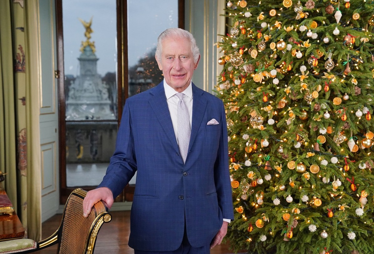 Regele Charles în timp ce pozează în fața bradului de Crăciun