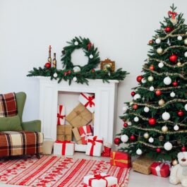 Un brad de Crăciun pus lângă un șemineu și un fotoliu pentru a ilustra unde se punde bradul de Crăciun în casă