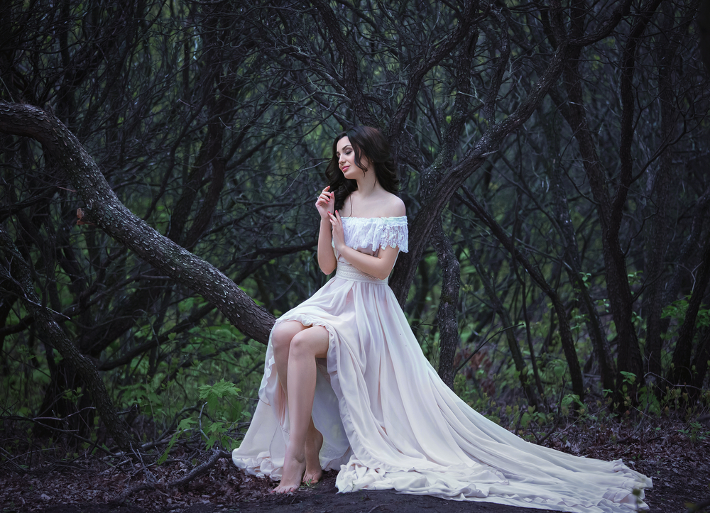 Fată frumoasă în orchie albă stă într-o pădure
