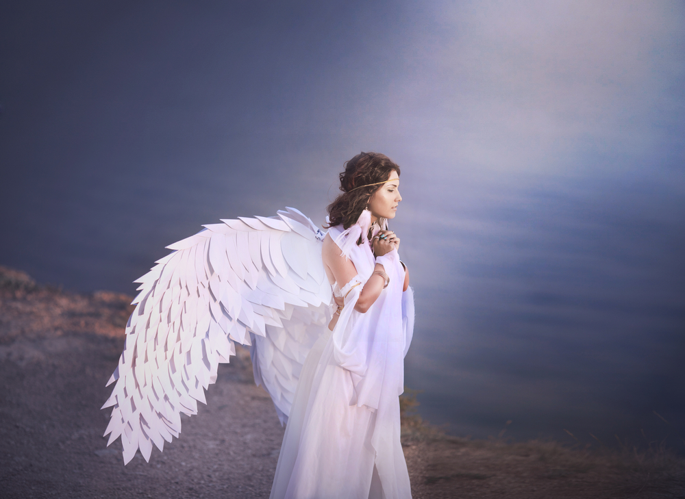 O femeie în rochie albă, cu aripi de înger în spate