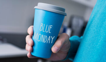 O femeie care ține în mână un pahar cu cafea de Blue Monday