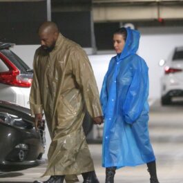 Kanye West într-o pelerină de ploaie maro și Bianca Censori într-o pelerină de ploaie albastră