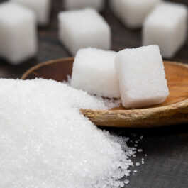 Zahăr vrac și cubulețe de zahăr, fotografiate în lingură din lemn sau pe masă