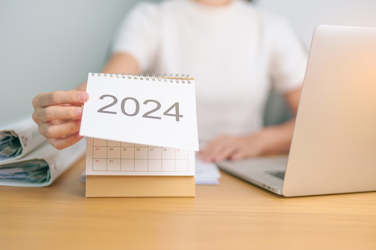 O femeie care stă la birou și pune anul 2024 pe calendar