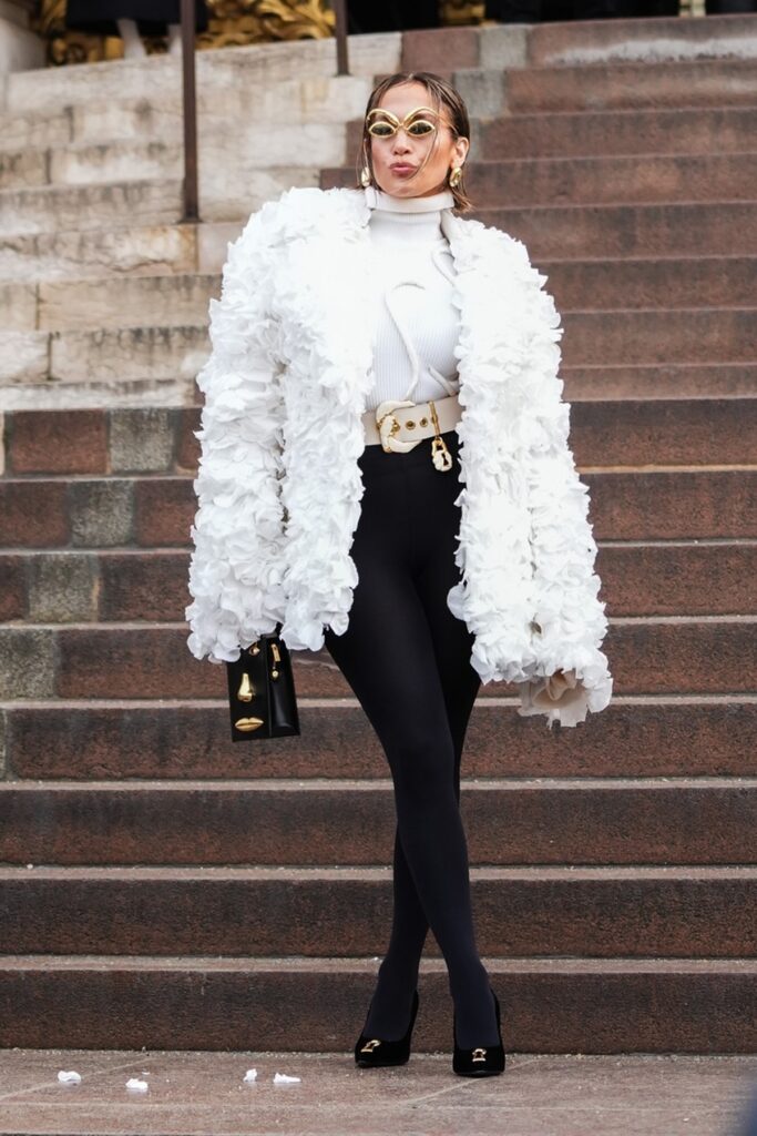 Jennifer Lopez într-o pereche de pantaloni negri și o haină din petale albe la Săptămâna Modei de la Paris 2024