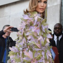 Jennifer Lopez purtând o rochie cu capă decorată cu flori la Săptămâna Modei de la Paris 2024