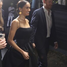 Meghan Markle într-o rochie neagră la brațul Prințului Harry