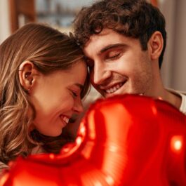 Un cuplu de îndrăgostiți care reprezintă flacăra geamănă și țin în mână un balon în formă de inimă