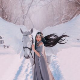 O femeie frumoasă care ține un cal alb de căpăstru în timp ce se află într-o pădure plină cu zăpadă și ilustrează zodia nefericită a lunii ianuarie 2024