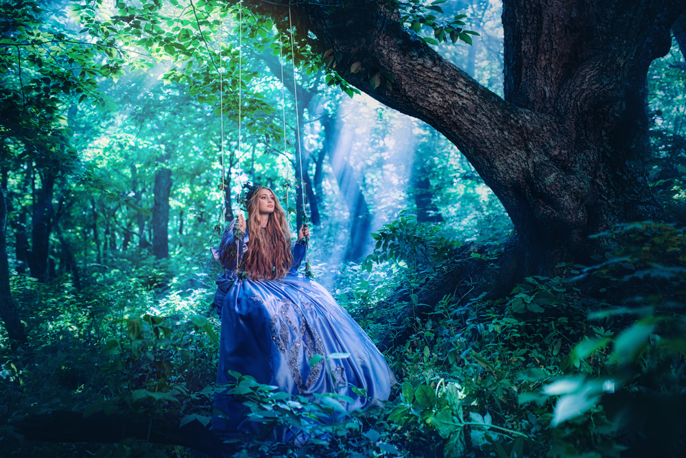 O femeie îmbrăcată frumos, pe un leagăn în pădure