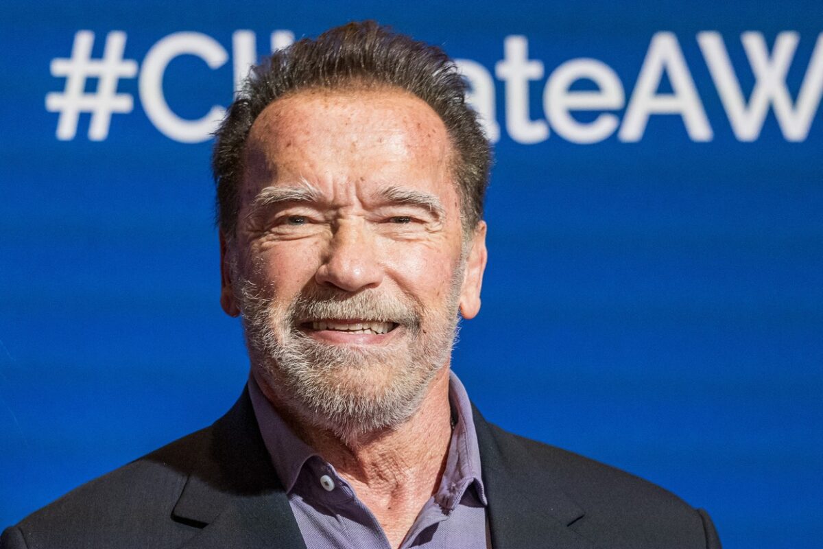 Arnold Schwarzenegger, într-un sacou negru, cu cămașă închisă la culoare, la un eveniment