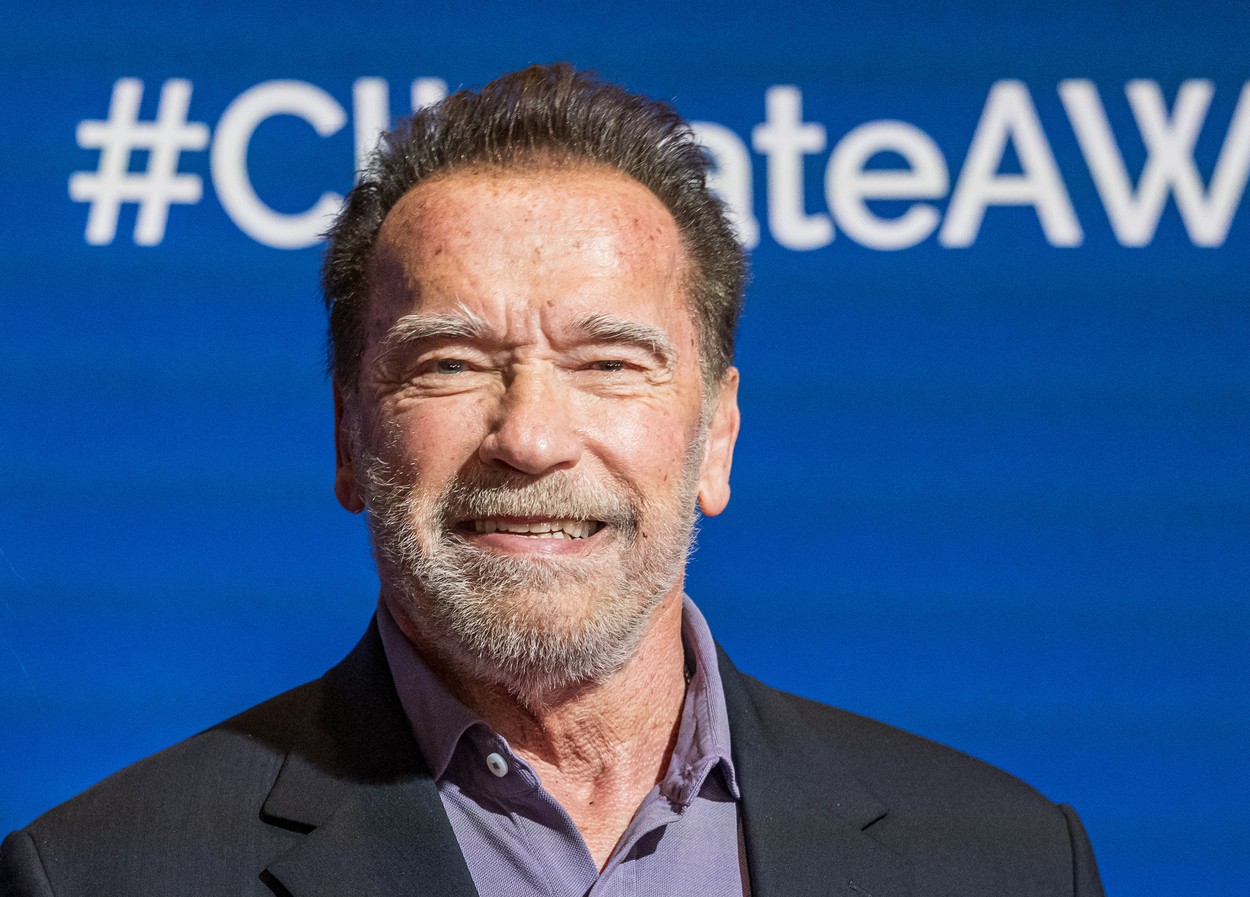 Arnold Schwarzenegger, într-un sacou negru, cu cămașă închisă la culoare, la un eveniment