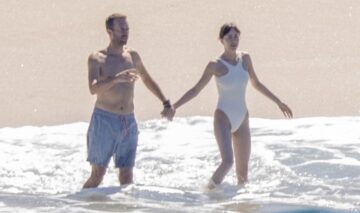 Dakota Johnson și Chris Martin în timp ce se țin de mână pe o plajă din Mexic