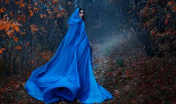 O femeie într-o rochie cu pelerină albastră, într-o pădure