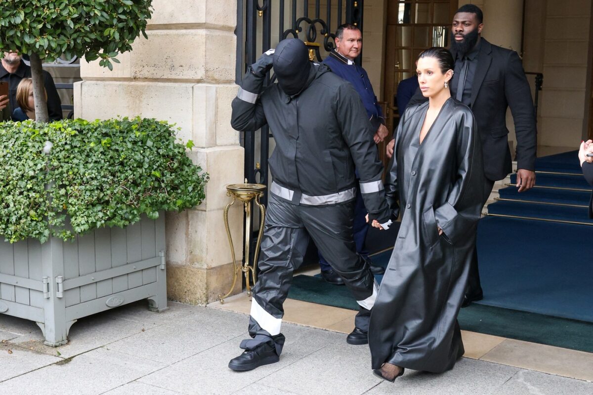 Kanye West, complet îmbrăcat, în timp ce o ține de mână pe Bianca Censori, îmbrăcată într-un pardesiu din piele