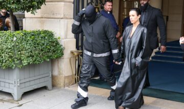 Kanye West, complet îmbrăcat, în timp ce o ține de mână pe Bianca Censori, îmbrăcată într-un pardesiu din piele