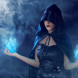 O femeie cu o glugă neagră pe cap care face magie