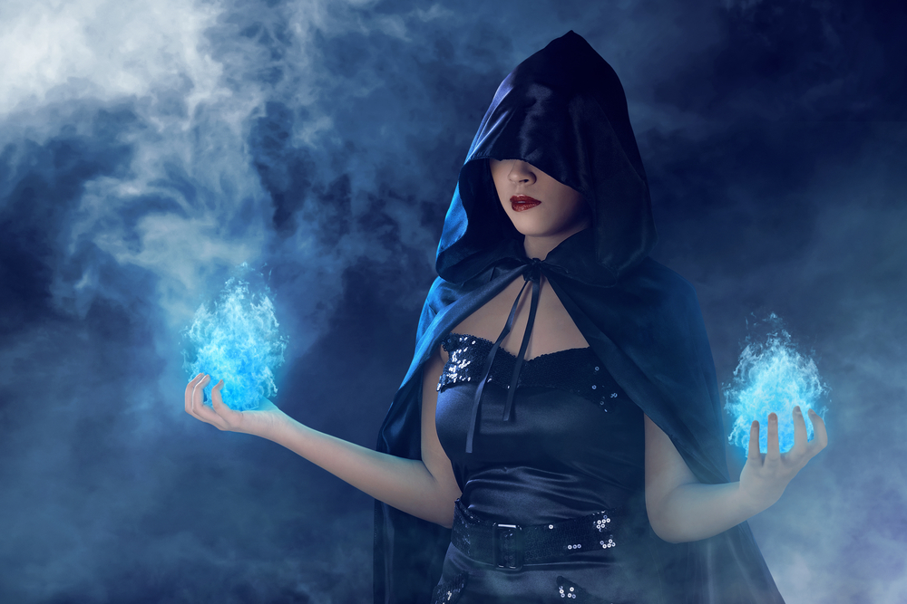 O femeie cu o glugă neagră pe cap care face magie