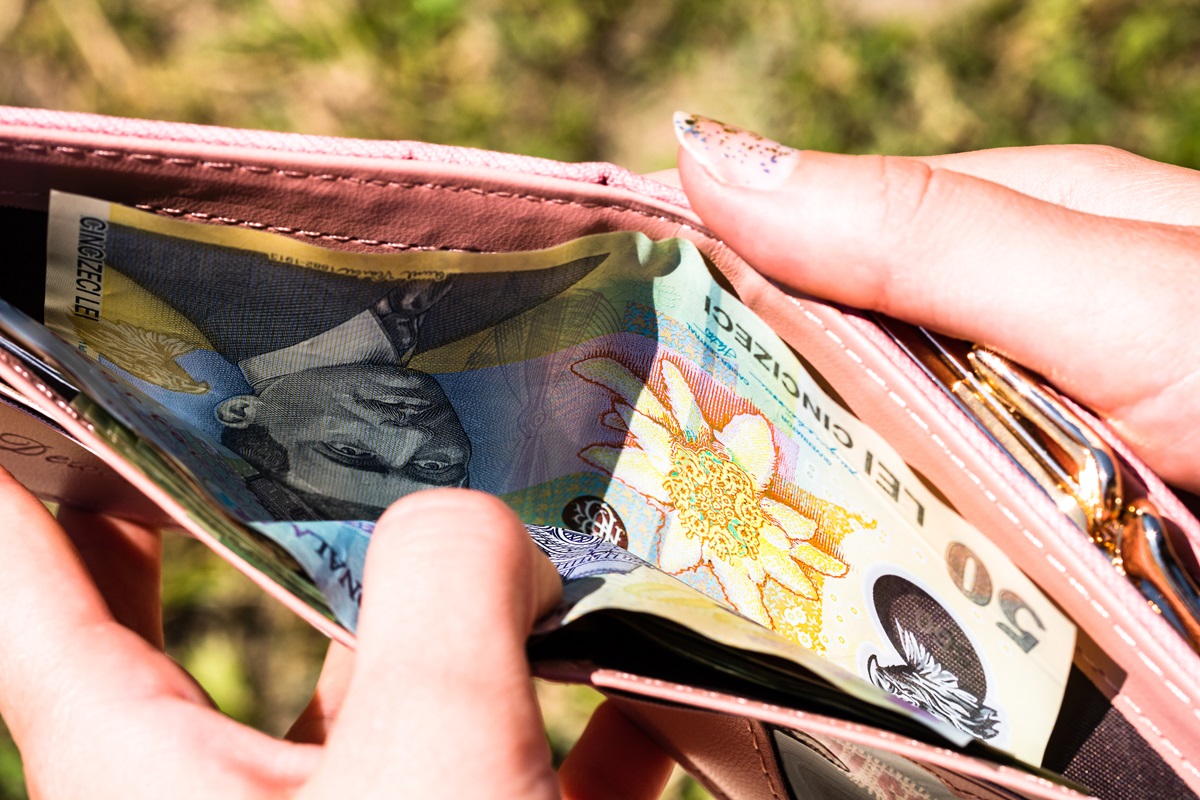 O mână de femeie care deschide un portofel plin cu bani
