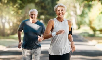 O femeie și un bărbat în vârstă care aleargă în parc împreună pentru a ilsutra cele mai bune exerciții pe care le poți face pe măsură ce înaintezi în vârstă