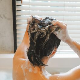 O femeie frumoasă care își spală corect părul în timp ce îl șamponează