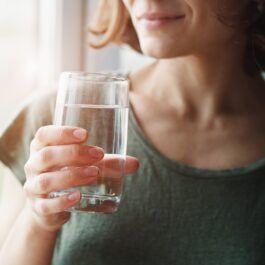 O femeie care bea un pahar cu apă