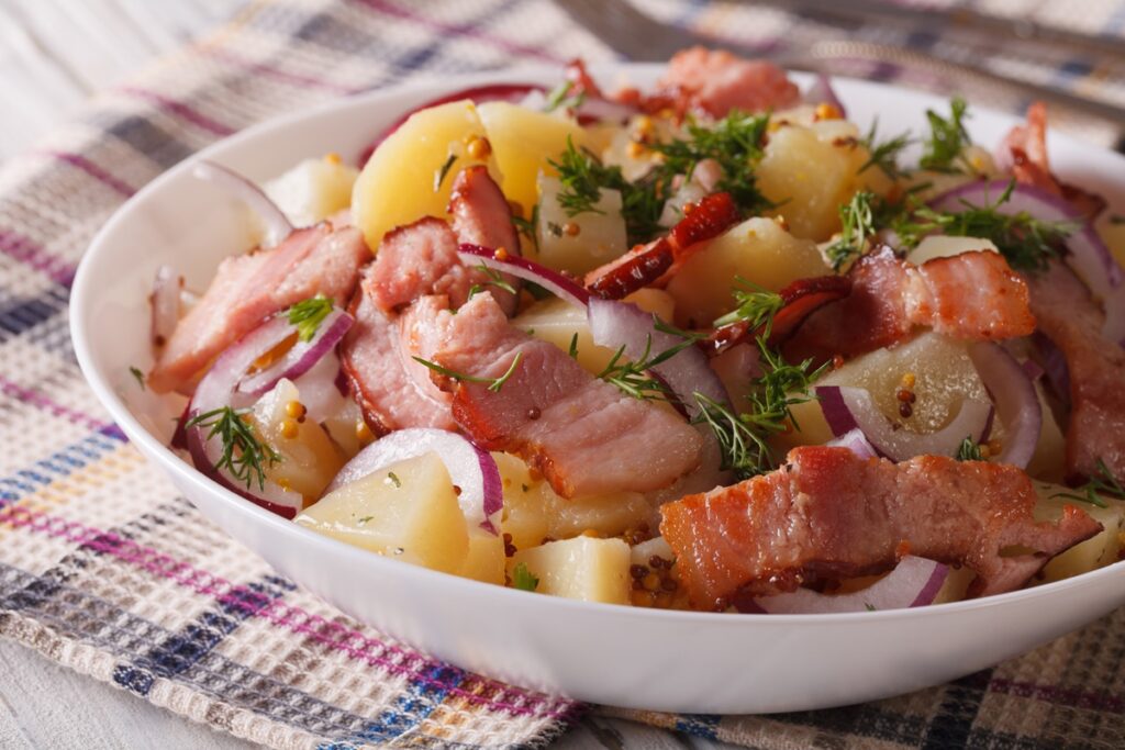 Salată caldă de cartofi, cu kaizer și ceapă roșie în bol alb