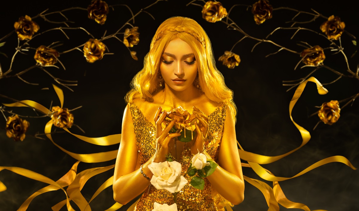 O femeie frumoasă care este vopsită cu auriu și ține în mână trandafiri pentru a ilustra una dintre cele trei zodii care îmbrățișează schimbarea în ziua de 19 februarie 2024
