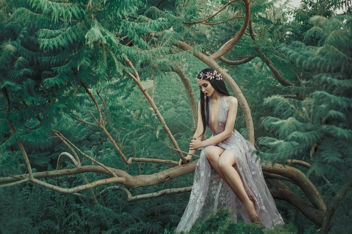 O femeie frumoasă care poartă o rochie nude și stă pe o creangă de copac pentru a ilustra una dintre cele trei zodii ghinioniste în ziua de 18 februarie 2024