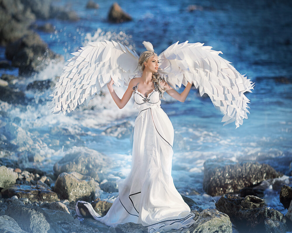 O femeie îmbrăcată într-o rochie albă, cu aripi de înger la spate