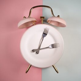 Un ceas format dintr-o farfurie, pe un fundal de roz cu gri