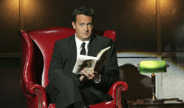Matthew Perry, pe un fotoliu, în timp ce citește o carte